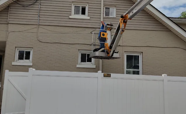 A TAP Heating and Cooling technician working from an aerial lift on a southwest Ohio home exterior